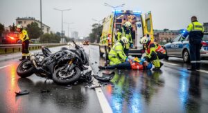 Motorcycle accident scene showing damage to the bike and emergency responders assisting the rider
